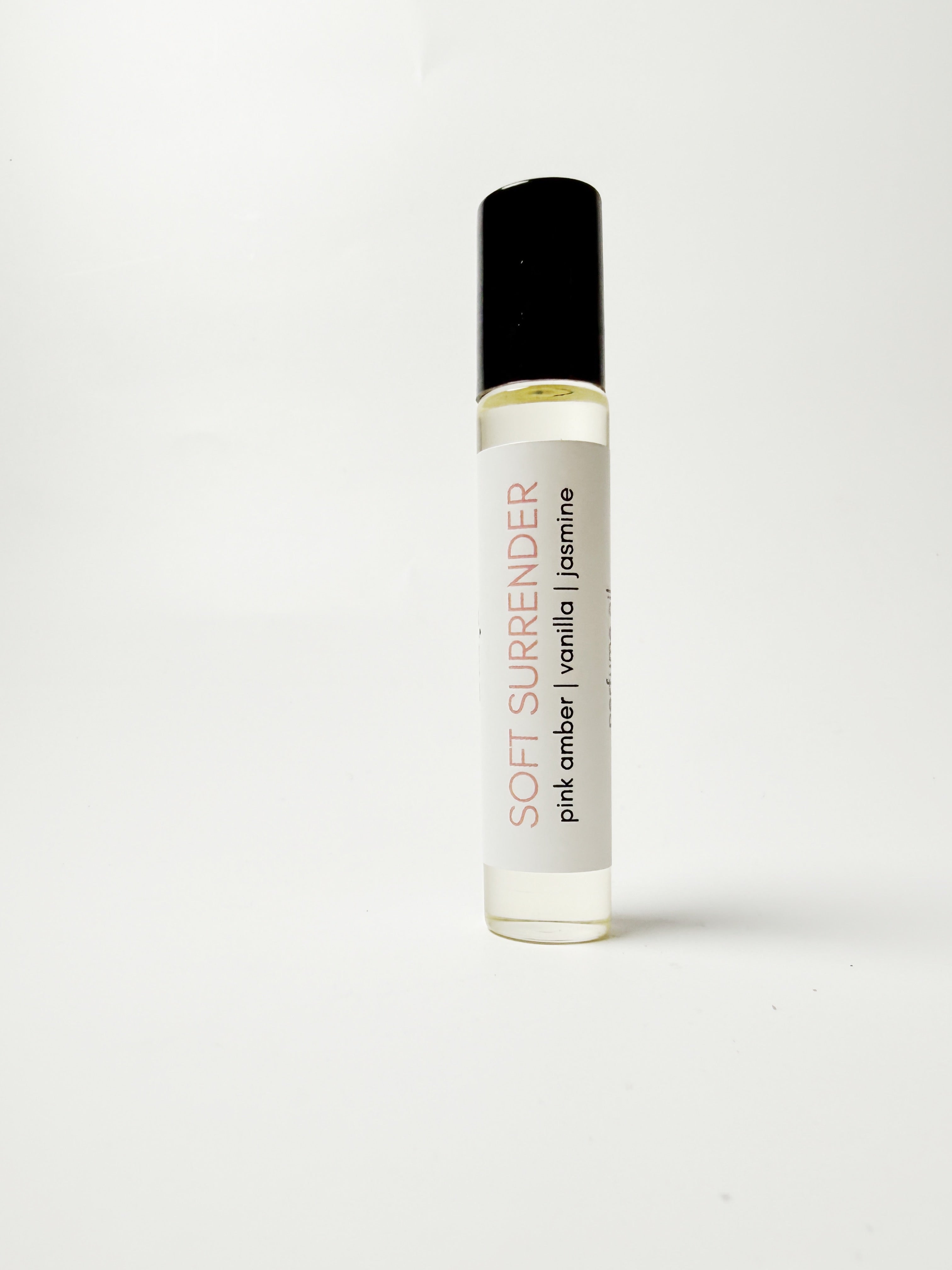 Roll-on bottle of 'Soft Surrender' perfume with a white label on a light gray background